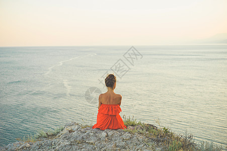 户外生活方式照片的女人穿着红色的衣服看着大海旅行背景旅游业图片