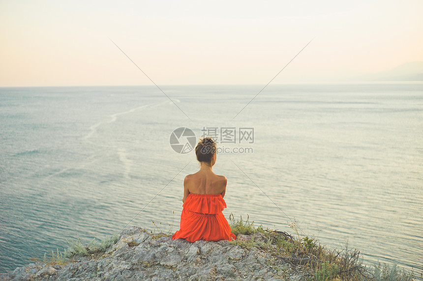 户外生活方式照片的女人穿着红色的衣服看着大海旅行背景旅游业图片