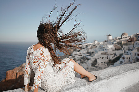 穿着白色连衣裙的快乐女人桑托里尼岛享受假期OIA看爱琴海欧洲夏季旅游目的地希腊岛屿背景图片