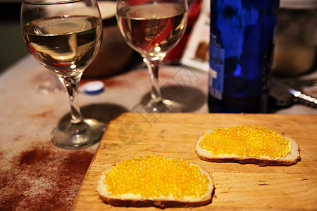厨房的黑板上自制的鲑鱼黄鱼子酱三明治背景上的瓶葡萄酒眼镜图片