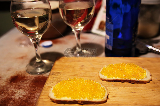 厨房的黑板上自制的鲑鱼黄鱼子酱三明治背景上的瓶葡萄酒眼镜图片