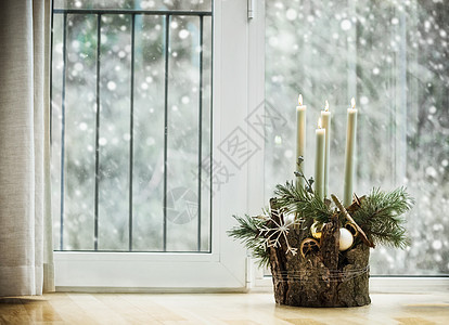 冬季舒适的家居装饰节日气氛与燃烧的蜡烛,冷杉枝雪花客厅的窗户与降雪装饰的降临花圈图片