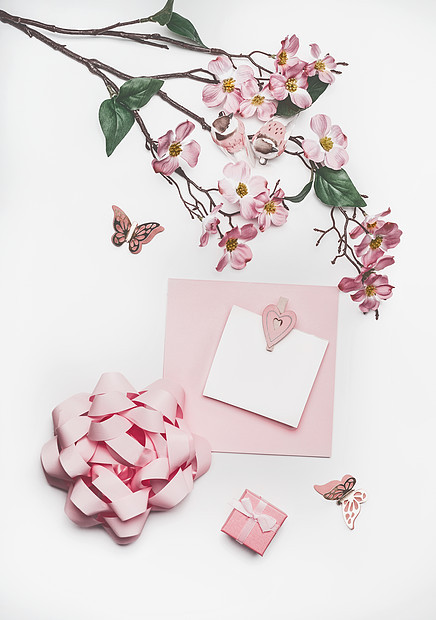 可爱的粉彩贺卡模拟与鲜花装饰,心,小礼盒蝴蝶结白色书桌背景,顶部视图,平躺婚礼邀请布局母亲节图片