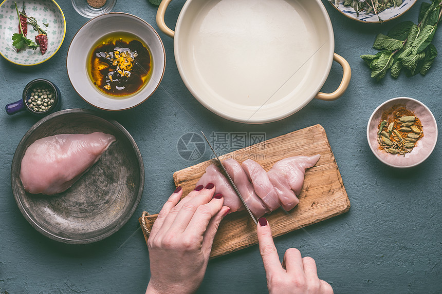 女手厨房餐桌背景上的木制切割板上切割鸡胸,配料顶部视图节食烹饪饮食健康食品的图片