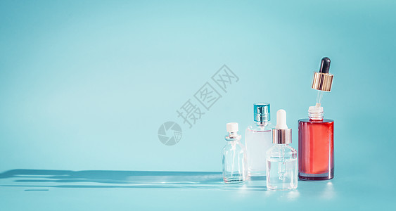 化妆品瓶产品与液体,吸管蓝色背景,正视图精华,爽肤水提取血清桌子上,正视图美容现代护肤理念与图片