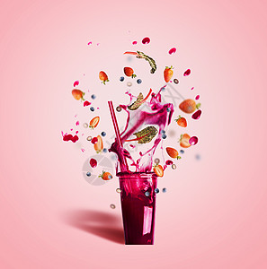 璃与饮用吸管紫色飞溅夏季饮料冰沙果汁与飞行浆果成分粉红色背景,正视图图片