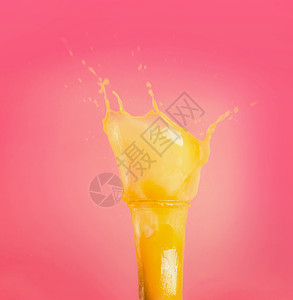 璃与黄色飞溅夏季饮料冰沙果汁粉红色背景,正视图图片