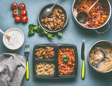健康平衡的午餐盒准备与藜麦,西红柿豆酱鸡肉厨房的桌子背景与食物锅碗,顶部视图图片