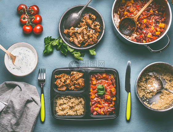 健康平衡的午餐盒准备与藜麦,西红柿豆酱鸡肉厨房的桌子背景与食物锅碗,顶部视图图片