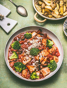 健康均衡的膳食锅与鸡肉片西红柿酱,绿色西兰花烤土豆,顶部视图图片