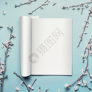 模型打开杂志目录粘贴蓝色桌背景与树枝白色樱花,顶部视图,平躺图片