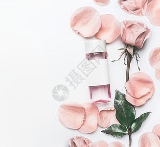 化妆瓶与部玫瑰水墨粉与精油,花花瓣白色书桌背景,顶部视图,品牌模拟美容护肤理念图片