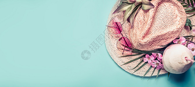 暑假横幅海滩配件草帽,棕榈叶,粉红色太阳眼镜,蓝色绿松石背景上的花椰子鸡尾酒,顶部景色热带度假旅游图片