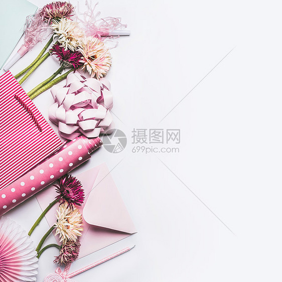 问候配件鲜花,蝴蝶结,丝带,粉红色礼品包装纸购物袋白色桌背景,顶部视图,平躺图片