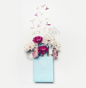 新鲜可爱的花蓝色纸购物袋白色桌背景,顶部视图,图片