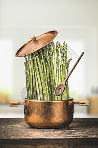芦笋烹饪锅与木勺乡村厨房桌子上,正视图健康素食饮食观念图片