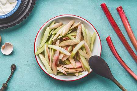 剥皮切片大黄碗厨房桌子背景,顶部视图季节食物大黄蛋糕的图片