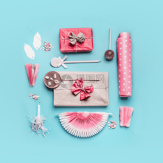 粉红色生日派配件带丝带的礼品盒,包装纸,巧克力棒棒糖,派风扇装饰淡蓝色背景上,顶部视图,平布局图片