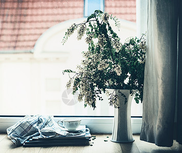 窗户上的叠杂志上放着花瓶花夏天的静物舒适的家庭场景,生活方式图片