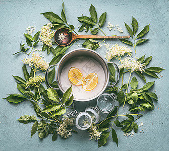 季节传统糖浆接骨骨木花的配料烹饪锅木勺糖柠檬璃瓶蓝色厨房桌子背景上,顶部视图图片