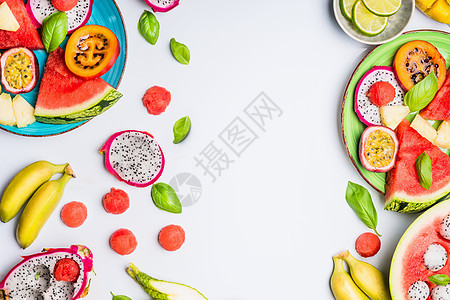 夏季清洁健康的生活方式背景与各种彩色切片热带水果浆果盘子碗白色背景,顶部视图,框架图片