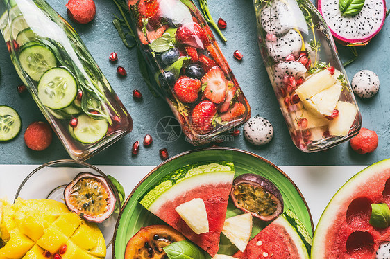 各种五颜六色的瓶装水与水果浆果,黄瓜,草药与成分桌子背景,顶部的视图美味的夏季清洁饮料,健康的生活方式健身图片