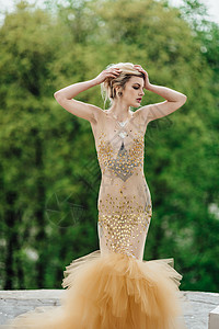 模特女孩穿着金色天老柱子附近的树林里摆姿势图片