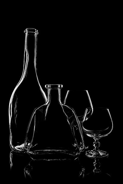 透明的白兰地瓶,背景为黑色,反光图片