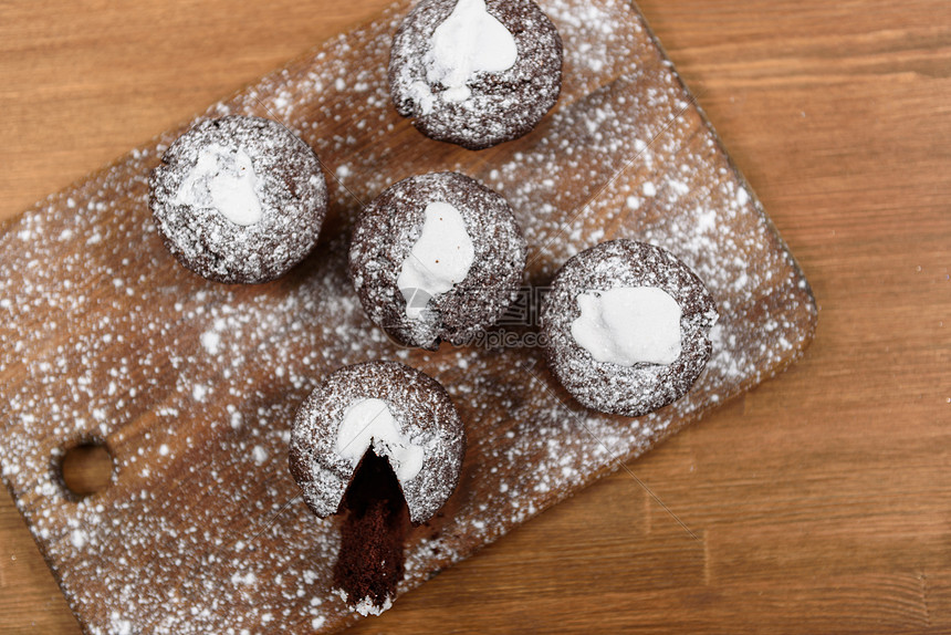 巧克力松饼与白色糖霜躺块撒了糖粉的木板上