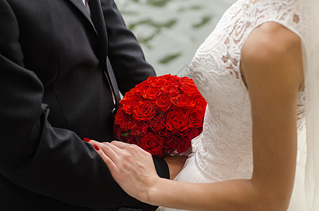 新娘新郎双手捧着红色的花背景图片