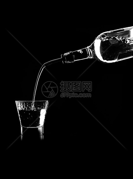 桌子上的个杯子里把白葡萄酒瓶子里倒进黑色背景的饮水机里