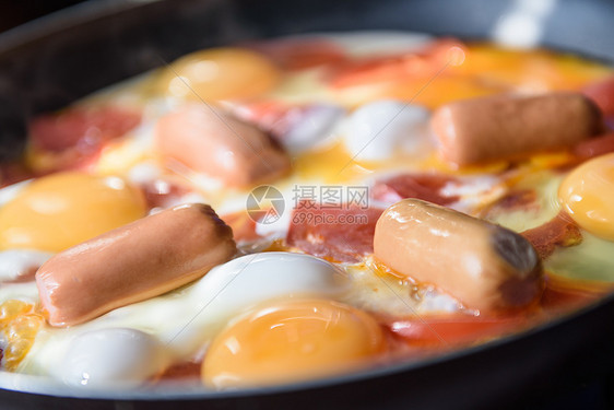 煎鸡蛋,香肠西红柿热锅上,烹饪早餐图片