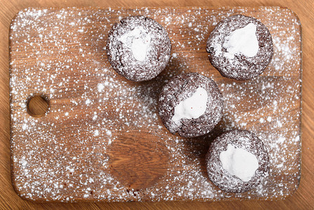 巧克力松饼与白色糖霜躺块撒了糖粉的木板上图片