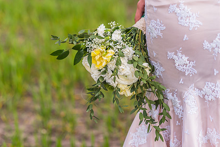 新娘手中的婚礼花礼服的背景上图片