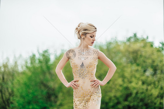 模特女孩穿着金色天老柱子附近的树林里摆姿势图片