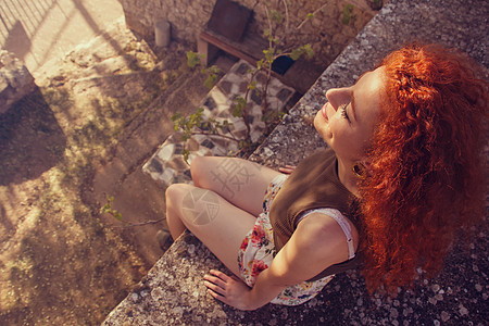 轻的红头发女人日落时享受阳光图片