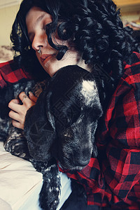 轻的黑发女人拥抱她的狗图片