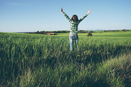 阳光明媚的日子里,轻的女人独自绿色的田野里图片
