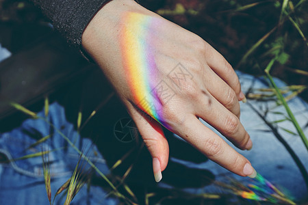 女手中的彩虹光图片