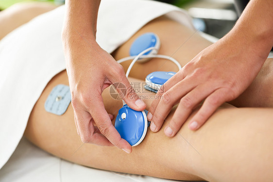物理治疗师应用电刺激物理治疗的轻妇女理疗中心腿部的医疗检查图片