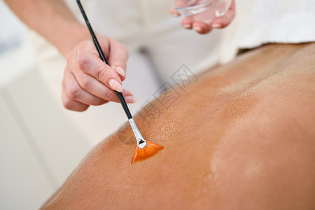 水疗保健中心接受油刷背部按摩治疗的妇女美美学背景图片
