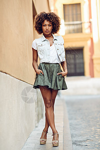 美国牛仔轻的黑人女人,阿夫罗发型,站街上城市背景下穿休闲衣服的女孩女穿裙子,牛仔背心高跟鞋背景