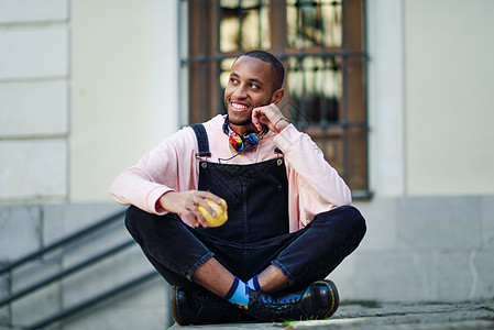 轻的黑人,坐城市台阶上吃苹果生活方式的图片