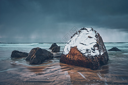 挪威峡湾海滩上的岩石被雪覆盖,暴风雨的天气里云斯卡桑登海滩,弗拉克斯塔德,洛福顿群岛,挪威长曝光运动模糊斯卡桑登图片