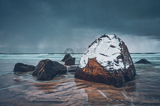 挪威峡湾海滩上的岩石被雪覆盖,暴风雨的天气里云斯卡桑登海滩,弗拉克斯塔德,洛福顿群岛,挪威长曝光运动模糊斯卡桑登图片