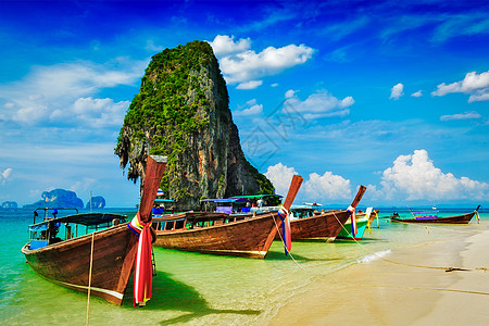 热带海滩上的长尾船,石灰石岩石,泰国克拉比泰国海滩上的长尾船图片