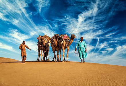 沙漠骆驼拉贾斯坦邦旅行背景两名印度来客骆驼司机与骆驼塔尔沙漠沙丘贾萨尔默,拉贾斯坦邦,印度两个来客骆驼司机带着骆驼塔尔背景
