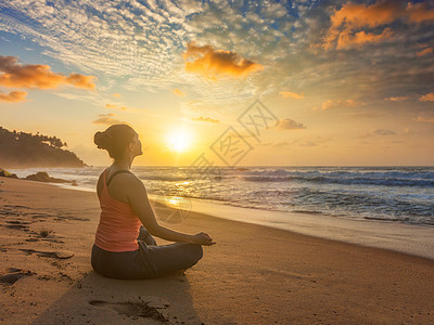 女人瑜伽冥想放松帕德马萨纳莲花阿萨纳姿势与中国泥德拉户外热带海滩日落与戏剧的太阳海滩上瑜伽的女人帕德马萨纳图片