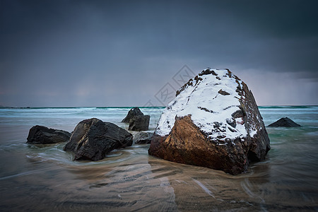 挪威峡湾海滩上的岩石被雪覆盖,暴风雨的天气里云斯卡桑登海滩,弗拉克斯塔德,洛福顿群岛,挪威长曝光运动模糊斯卡桑登图片