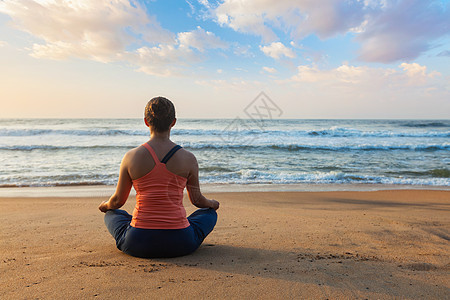 轻运动健康的女人瑜伽冥想放松帕德马萨纳莲花姿势与下巴泥德拉户外热带海滩日落轻的运动健康的女人海滩上瑜伽图片